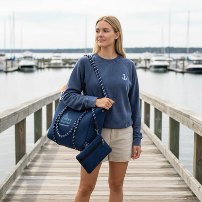 Woman on a marina dock carrying a navy blue Chicks Marina perforated neoprene tote bag with rope handles and pouch.