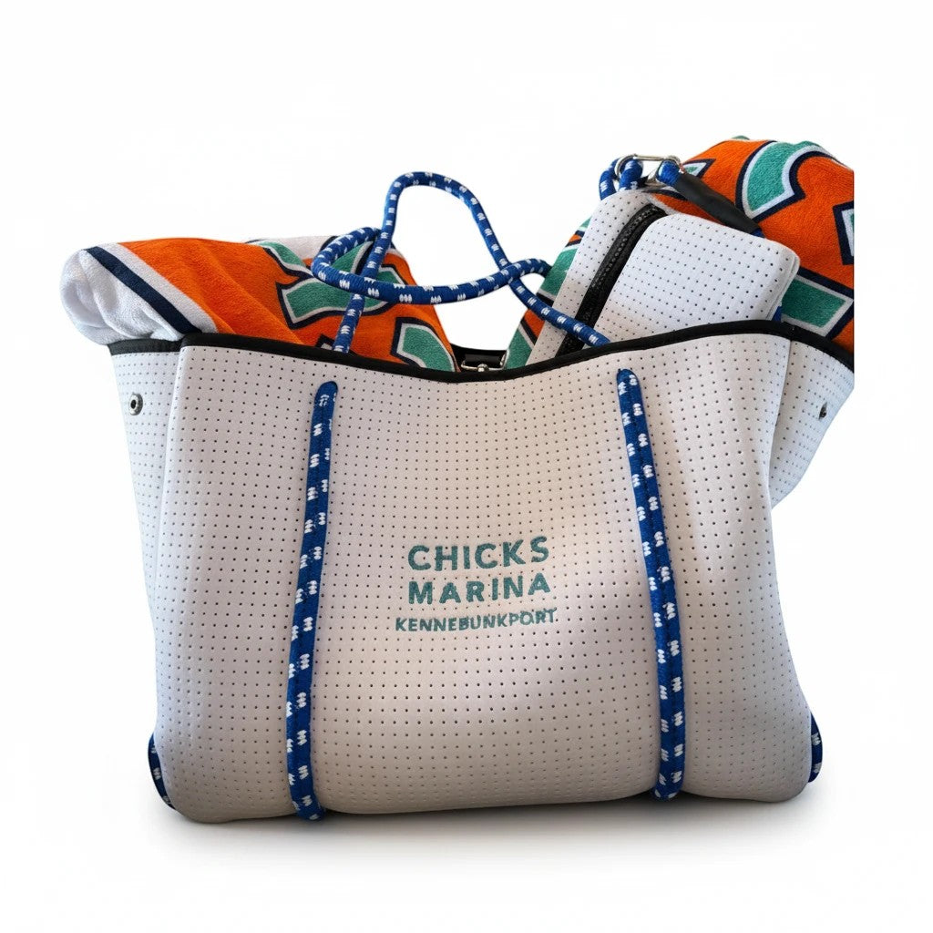 Chicks Marina white perforated neoprene tote bag with blue rope handles and matching pouch, filled with beach gear.