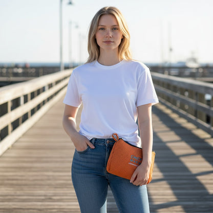 Woman holding an orange Chicks Marina pop pouch with zipper on a wooden pier, perfect for travel and organization.