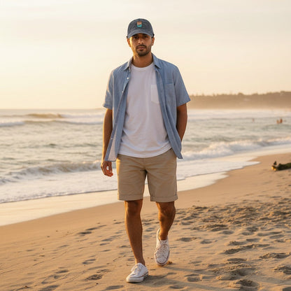 A man wearing a Chicks Marina salt wash corduroy cap walking on a beach at sunset.
